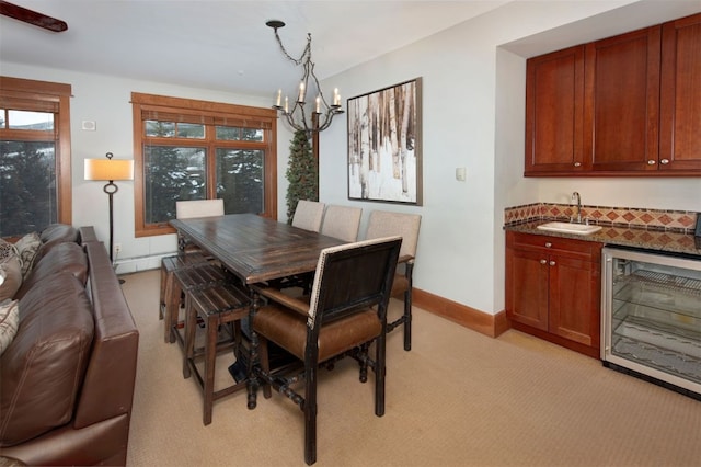 dining space with an inviting chandelier, light colored carpet, wine cooler, and sink