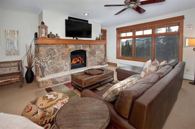 carpeted living room with ceiling fan, baseboard heating, and a stone fireplace