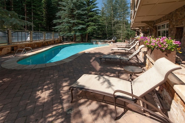 view of pool featuring a hot tub and a patio