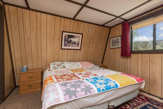 bedroom with carpet flooring and wood walls