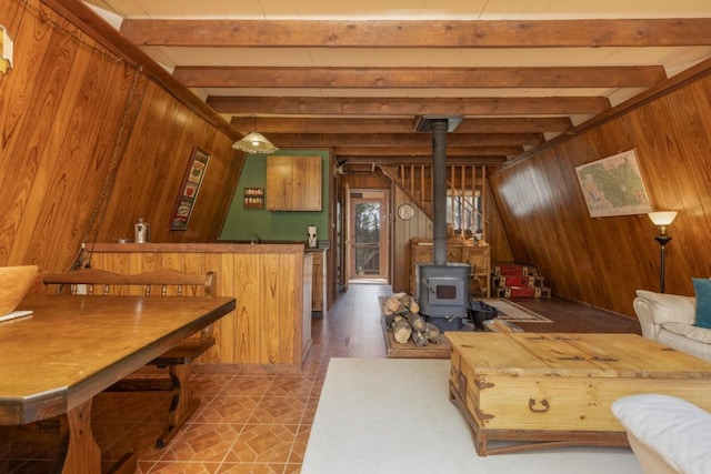 living room featuring beam ceiling, a wood stove, and wooden walls