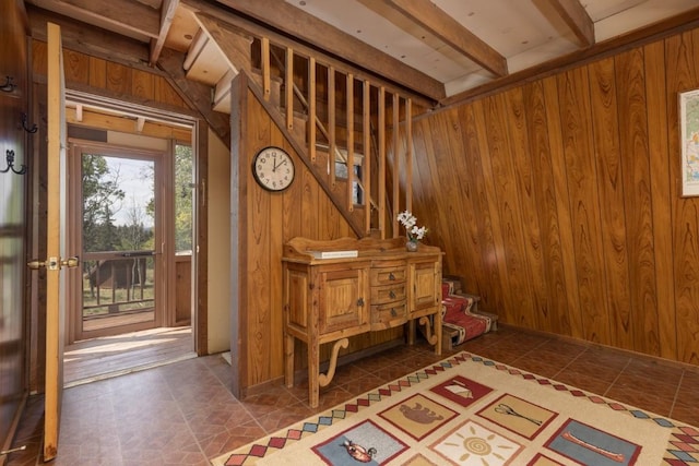 misc room with beam ceiling, dark tile patterned floors, and wooden walls