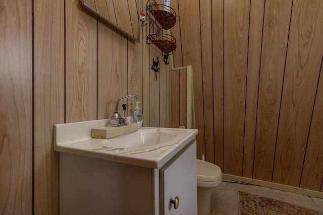 bathroom featuring vanity, toilet, and wooden walls