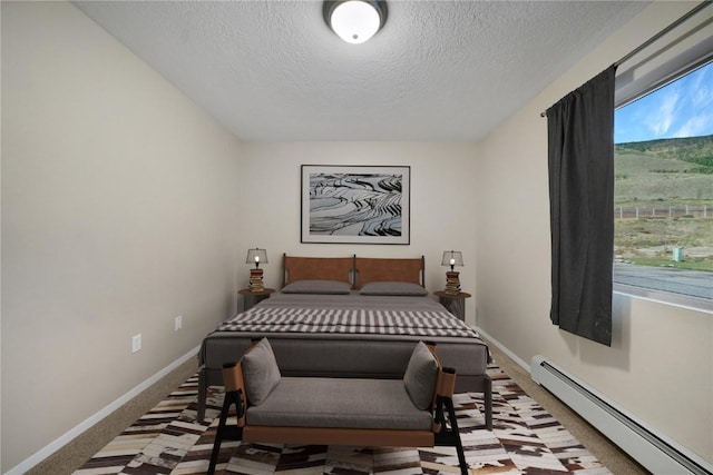 bedroom featuring a textured ceiling, carpet floors, and baseboard heating