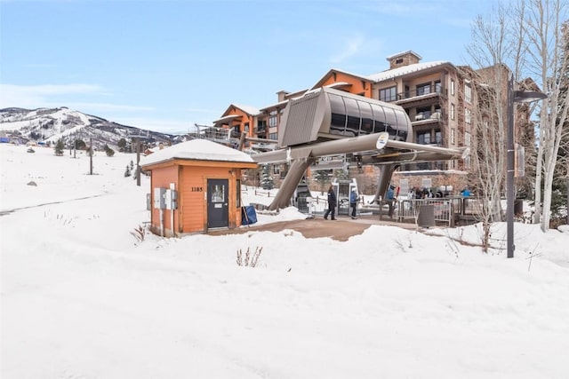 snow covered rear of property featuring a mountain view