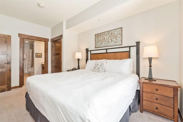 bedroom featuring baseboards, connected bathroom, and light colored carpet