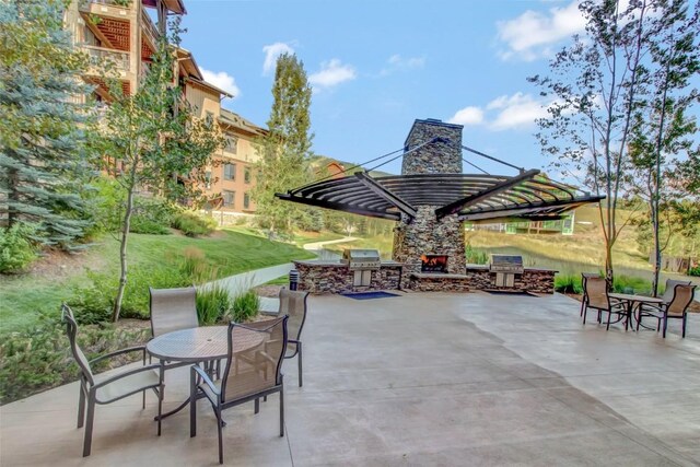 view of patio featuring an outdoor stone fireplace, outdoor dining area, an outdoor kitchen, and grilling area