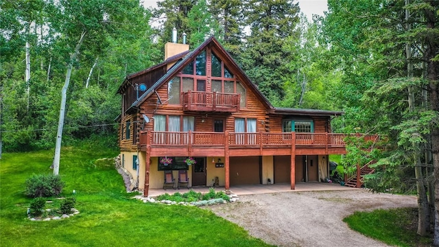 view of front of house with a balcony, driveway, log siding, a chimney, and a front lawn