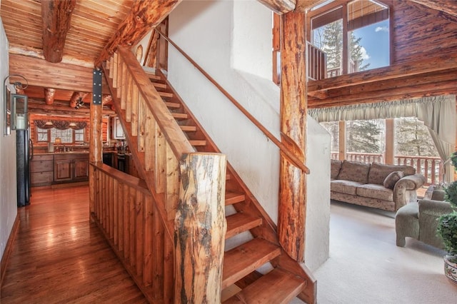 stairs with a wealth of natural light, a towering ceiling, beamed ceiling, and wood ceiling