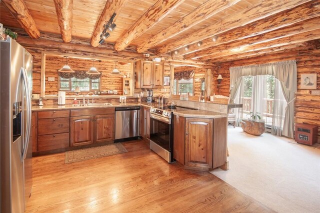 kitchen with sink, log walls, hanging light fixtures, kitchen peninsula, and appliances with stainless steel finishes