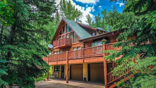 rear view of property with an attached garage, log exterior, and driveway