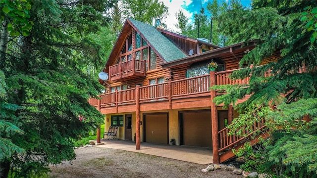 rear view of property featuring log siding, a garage, driveway, and roof with shingles