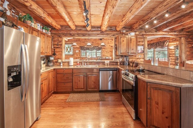 kitchen featuring a peninsula, a sink, rail lighting, appliances with stainless steel finishes, and wooden ceiling