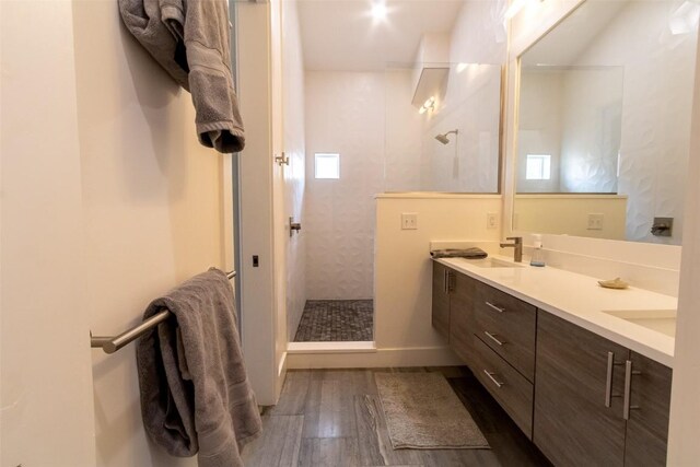 bathroom with hardwood / wood-style floors, vanity, and a tile shower