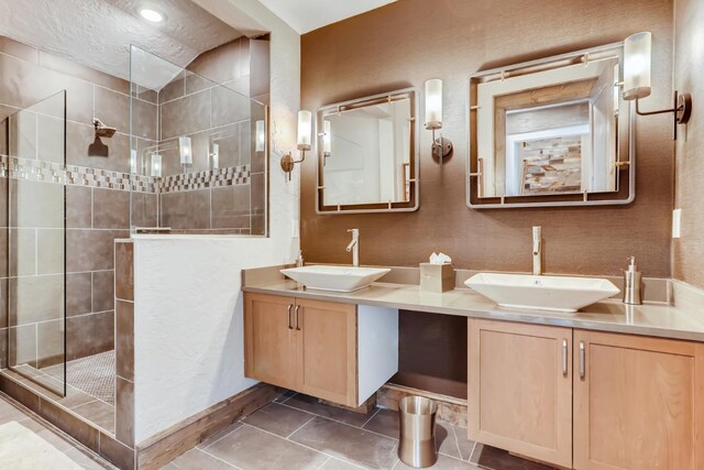 bathroom featuring a textured ceiling, vanity, a tile shower, and tile patterned flooring