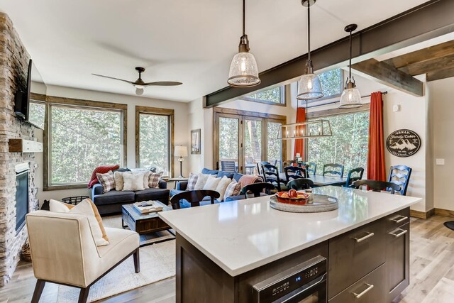 kitchen featuring a center island, a brick fireplace, hanging light fixtures, light hardwood / wood-style flooring, and ceiling fan