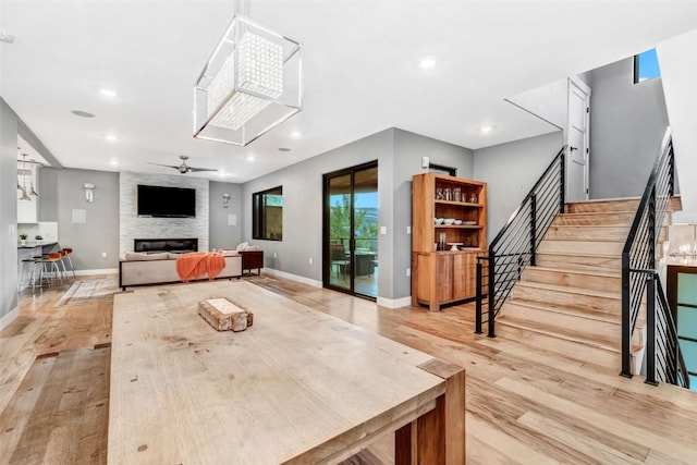 dining room with ceiling fan, a fireplace, and light hardwood / wood-style flooring