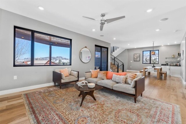 living room with hardwood / wood-style floors, a stone fireplace, and ceiling fan