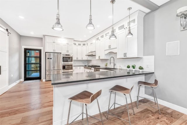 kitchen featuring white cabinets, a barn door, sink, and stainless steel appliances