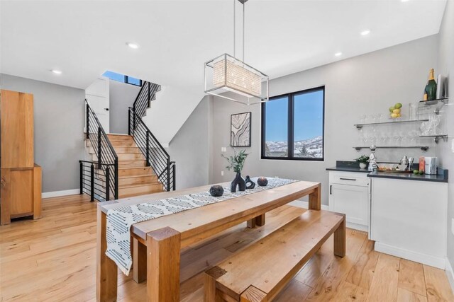 kitchen with white cabinetry, range hood, stainless steel appliances, and hanging light fixtures