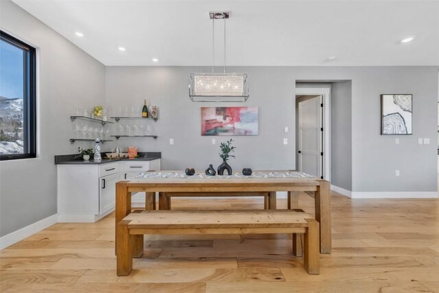 dining space featuring bar area, an inviting chandelier, and light hardwood / wood-style flooring