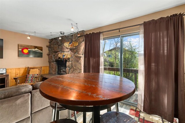 dining room featuring track lighting and a stone fireplace