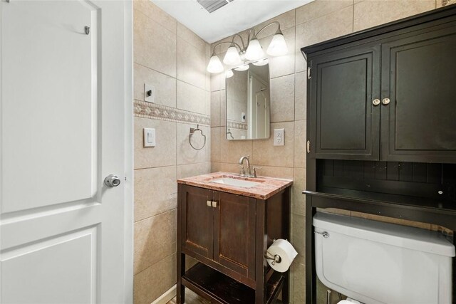 bathroom with vanity, toilet, tile walls, and tasteful backsplash