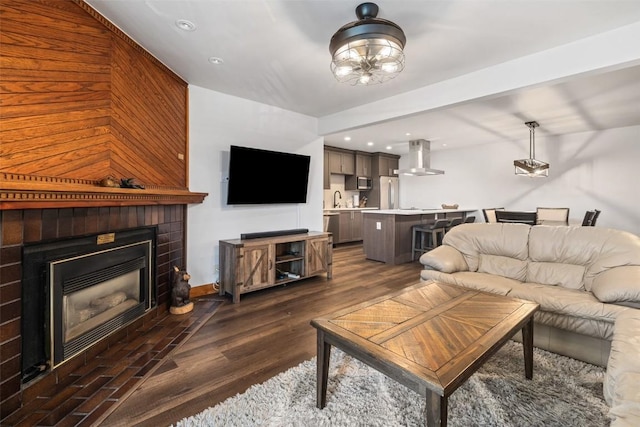 living room with a brick fireplace, dark hardwood / wood-style floors, and sink