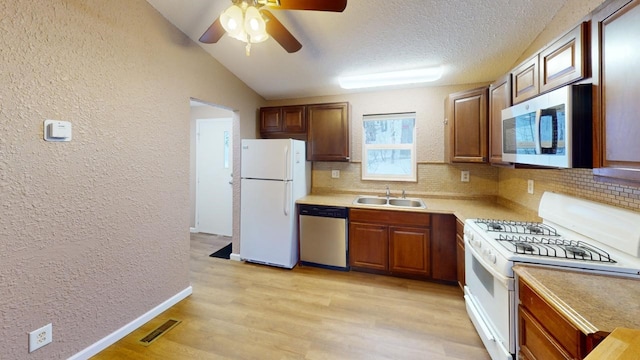 kitchen featuring appliances with stainless steel finishes, tasteful backsplash, sink, a textured ceiling, and light hardwood / wood-style flooring