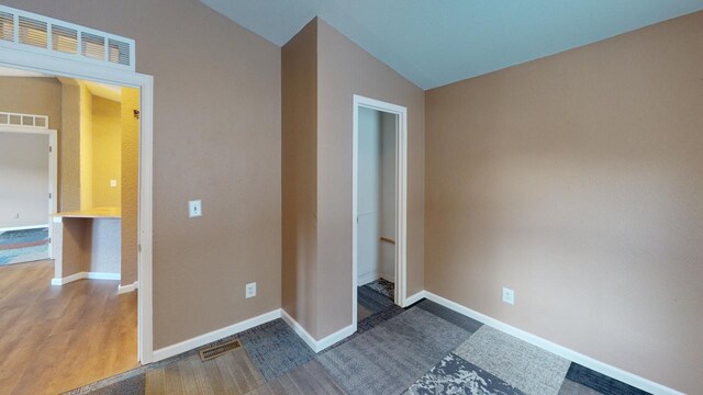 unfurnished bedroom featuring vaulted ceiling and wood-type flooring