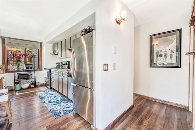 kitchen with appliances with stainless steel finishes, dark hardwood / wood-style floors, and range hood