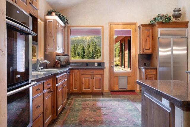 kitchen with dark tile patterned floors, stainless steel built in fridge, lofted ceiling, and tasteful backsplash