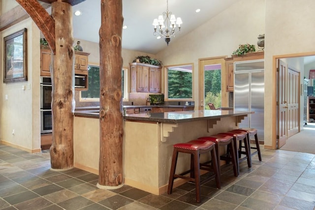 kitchen with pendant lighting, a breakfast bar, appliances with stainless steel finishes, kitchen peninsula, and a chandelier