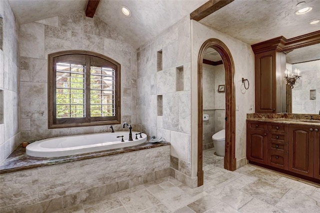 bathroom with tiled bath, lofted ceiling, toilet, vanity, and tile walls