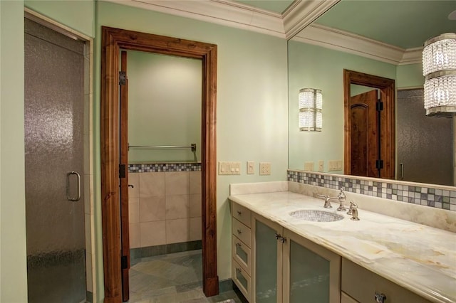 bathroom featuring crown molding, vanity, a shower with shower door, and tile walls