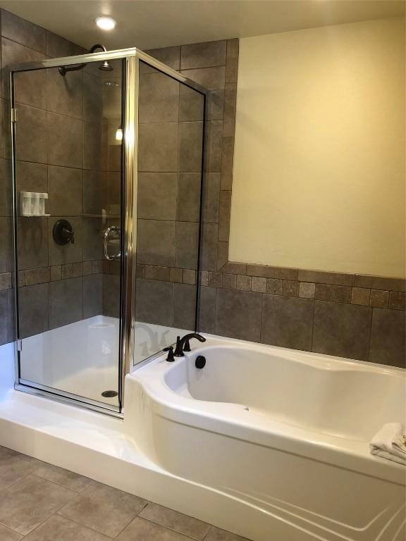 bathroom with a shower stall, a bath, and tile patterned floors