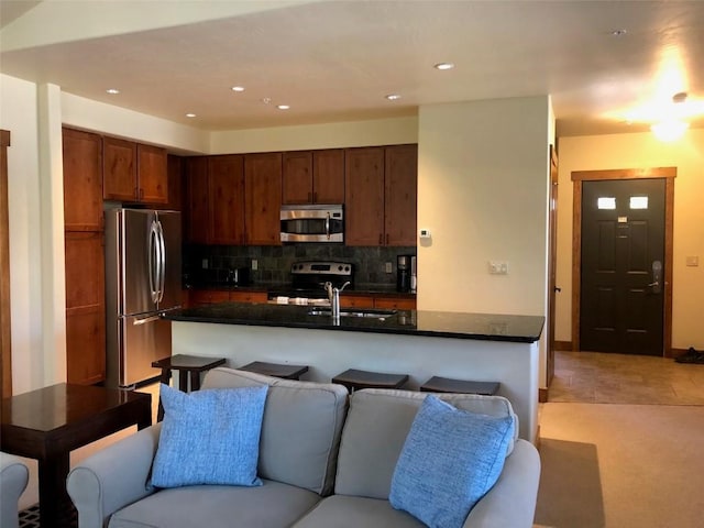 kitchen with dark countertops, open floor plan, appliances with stainless steel finishes, and a sink