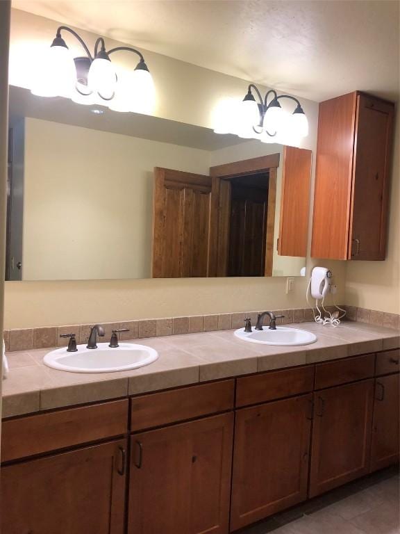 full bath featuring double vanity, tile patterned flooring, and a sink