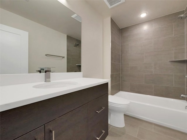 full bathroom featuring tile patterned flooring, vanity, tiled shower / bath, and toilet