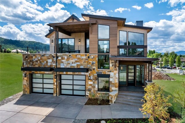 contemporary house featuring a garage, a mountain view, and a front lawn