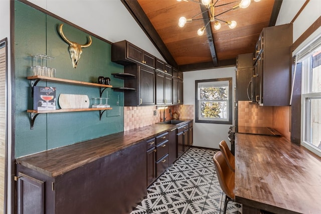 kitchen featuring lofted ceiling with beams, open shelves, a sink, wooden ceiling, and tasteful backsplash