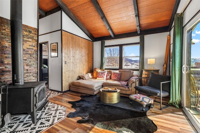 living area featuring wooden ceiling, a wood stove, vaulted ceiling with beams, and wood finished floors