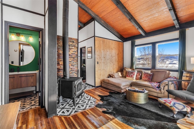 living area featuring lofted ceiling with beams, wood ceiling, a wood stove, and wood finished floors