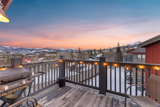 snow covered deck featuring a mountain view and a grill