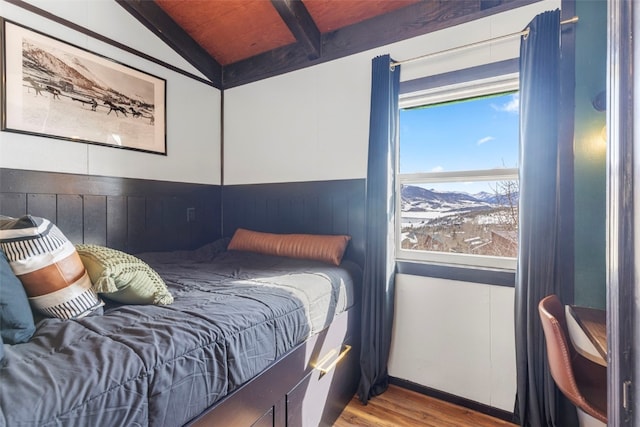 bedroom with lofted ceiling with beams, wood ceiling, and wood finished floors