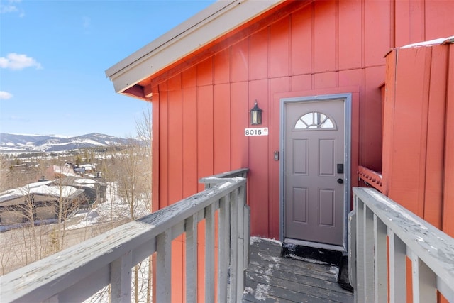 snow covered property entrance featuring a mountain view and board and batten siding