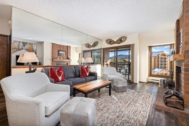 living room featuring a brick fireplace, dark hardwood / wood-style floors, and a textured ceiling