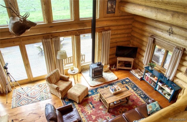 living room with wood-type flooring, a high ceiling, log walls, and french doors