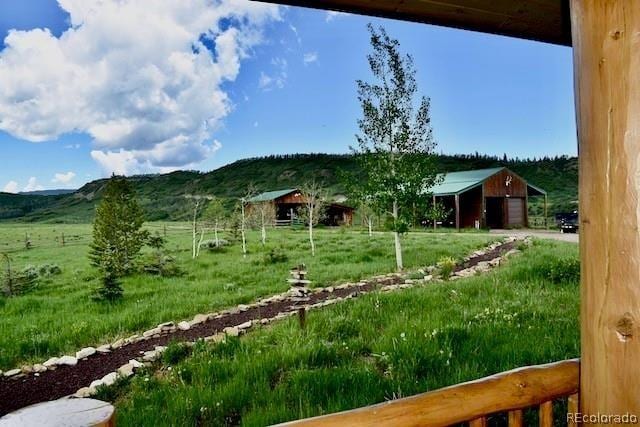 view of yard featuring a mountain view, a rural view, and an outbuilding