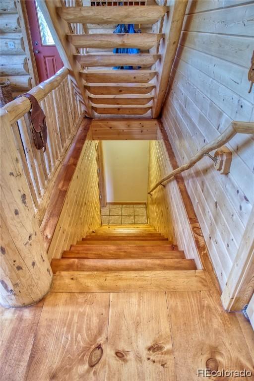 stairway featuring log walls and wood-type flooring